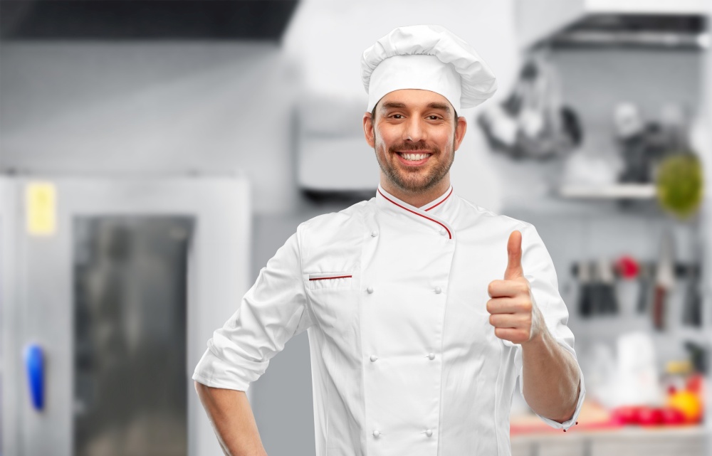 cooking, culinary and people concept - happy smiling male chef in toque showing thumbs up over restaurant kitchen background. smiling male chef in toque showing thumbs up