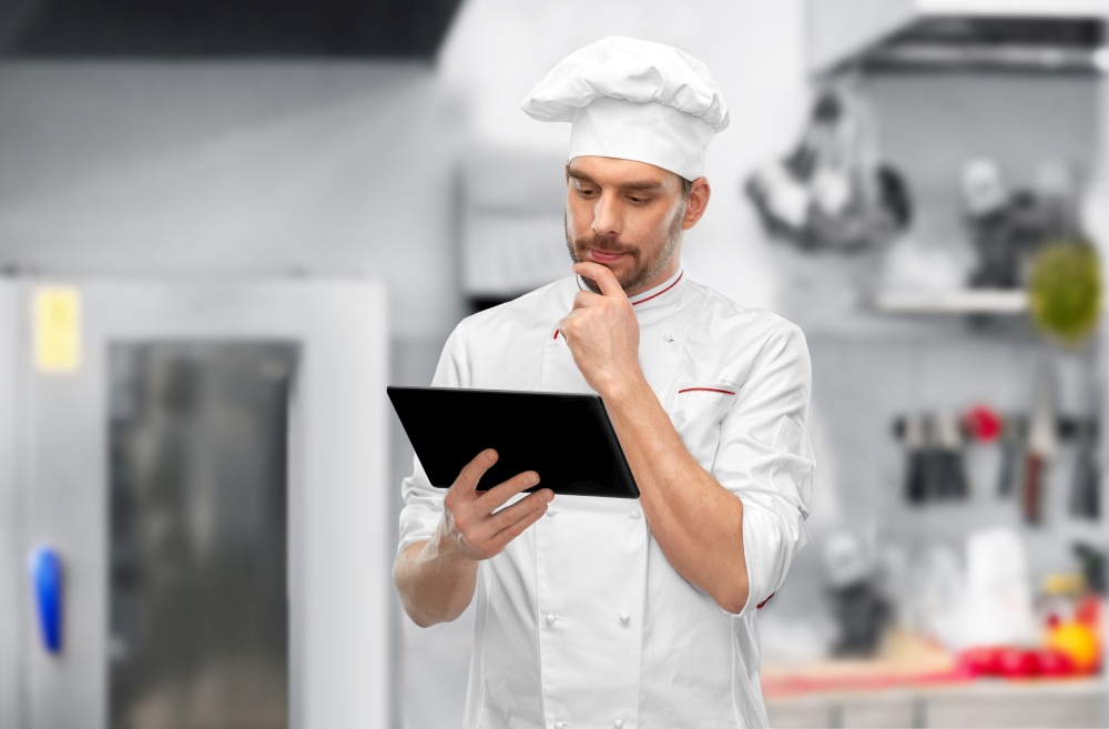 cooking, culinary and people concept - male chef in toque with tablet pc computer over restaurant kitchen background. male chef with tablet pc at restaurant kitchen