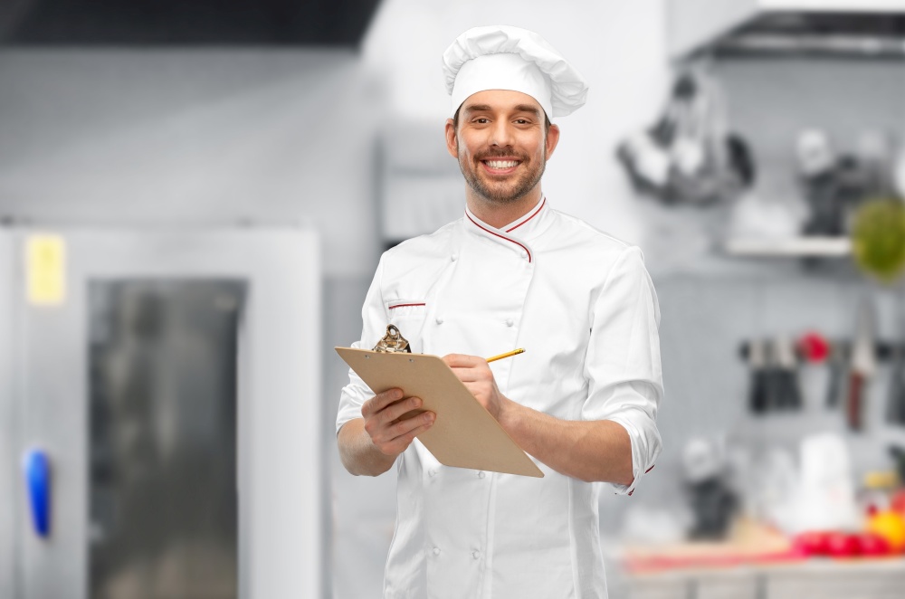 cooking, culinary and people concept - happy smiling male chef with clipboard and pencil over restaurant kitchen background. happy smiling male chef with clipboard and pencil