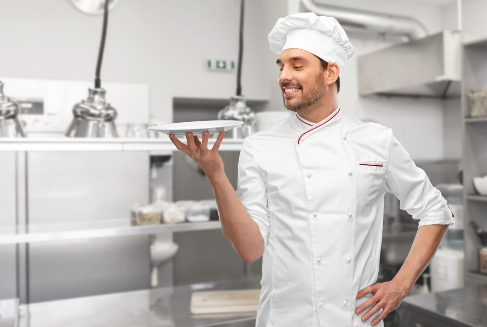 cooking, culinary and people concept - happy smiling male chef in toque holding empty plate over grey background. happy smiling male chef holding empty plate