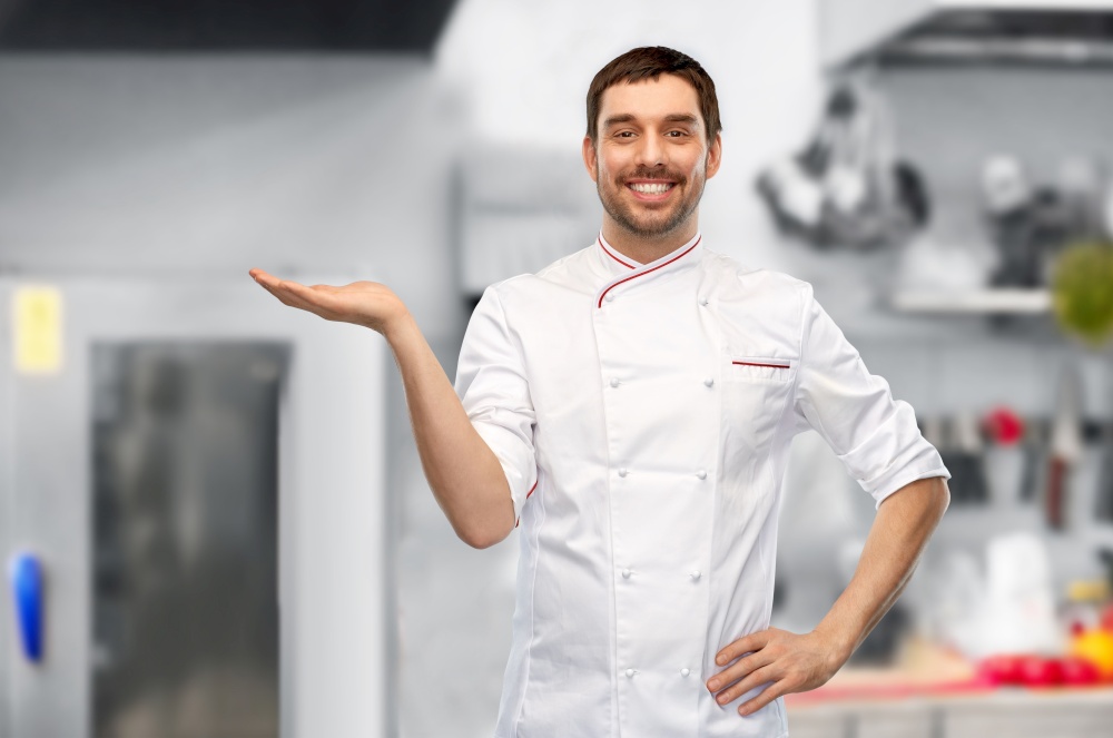 cooking, culinary and people concept - happy smiling male chef in jacket holding something on hand over grey background. happy smiling male chef holding something on hand