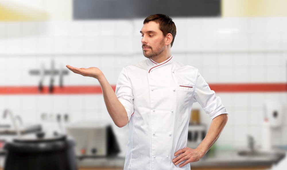 cooking, culinary and people concept - male chef in jacket holding something on hand over grey background. male chef holding something on hand