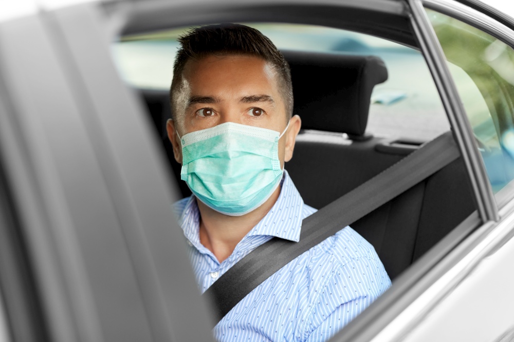 safety, health care and people concept - young man or male passenger wearing face protective medical mask for protection from virus disease in car. man or male passenger wearing mask in car