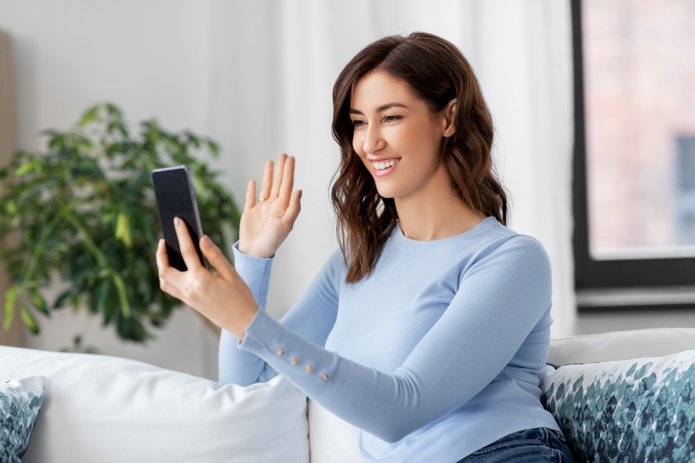 technology, communication and people concept - smiling woman with smartphone having video call at home. woman with smartphone having video call at home