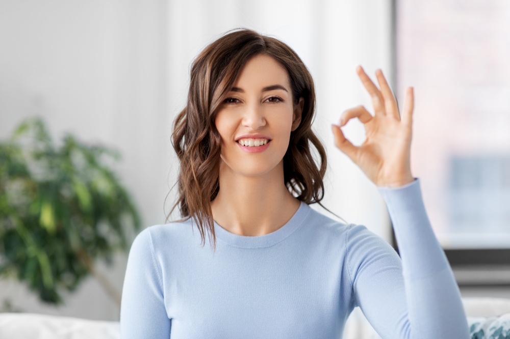 gesture and people concept - happy smiling woman showing ok hand sign at home. happy smiling woman showing ok hand sign at home