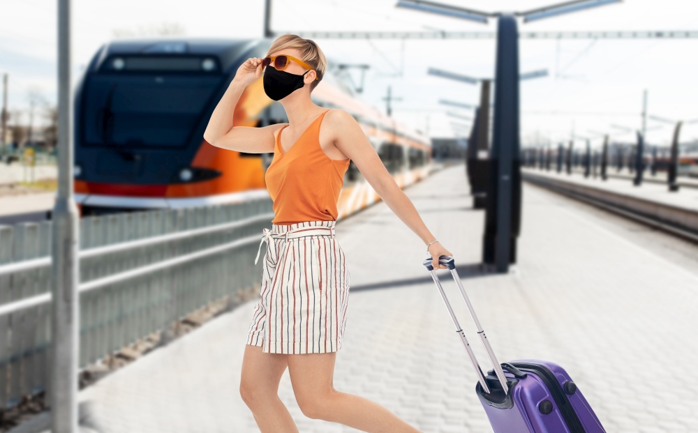 tourism, vacation and people concept - smiling young woman or teenage girl with travel bag over train on railway station on background. woman in mask with travel bag over train