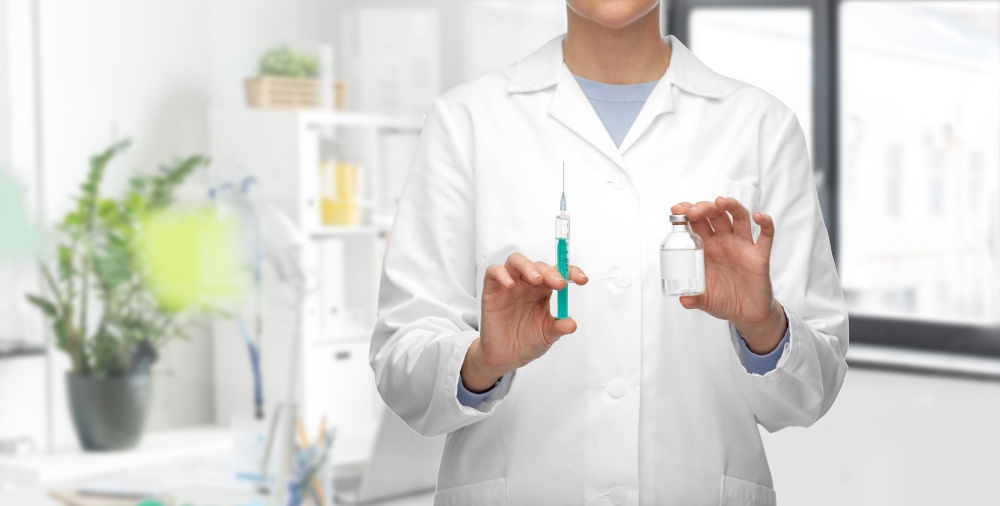 medicine, vaccination and healthcare concept - close up of female doctor or nurse with drug and syringe over medical office at hospital background. doctor with medicine and syringe at hospital