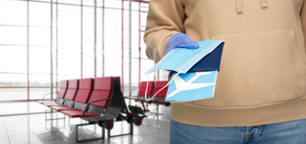 travel, tourism and health care concept - close up of woman in gloves with mask, passport and air ticket over airport terminal background. woman with mask, passport and ticket at airport