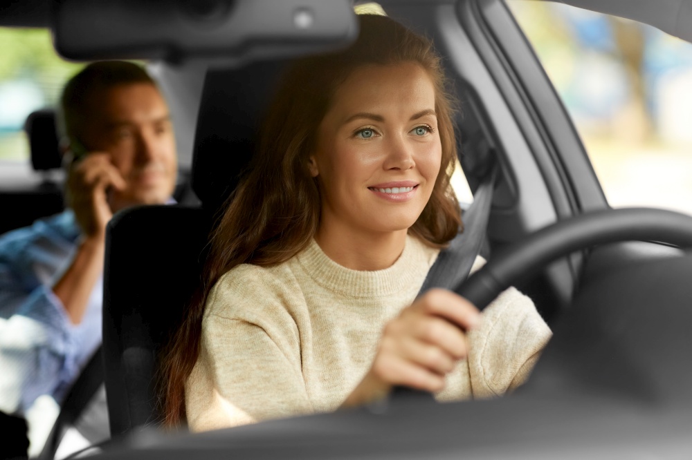 transportation, vehicle and people concept - happy smiling female driver driving car with male passenger calling on phone. female driver driving car with male passenger