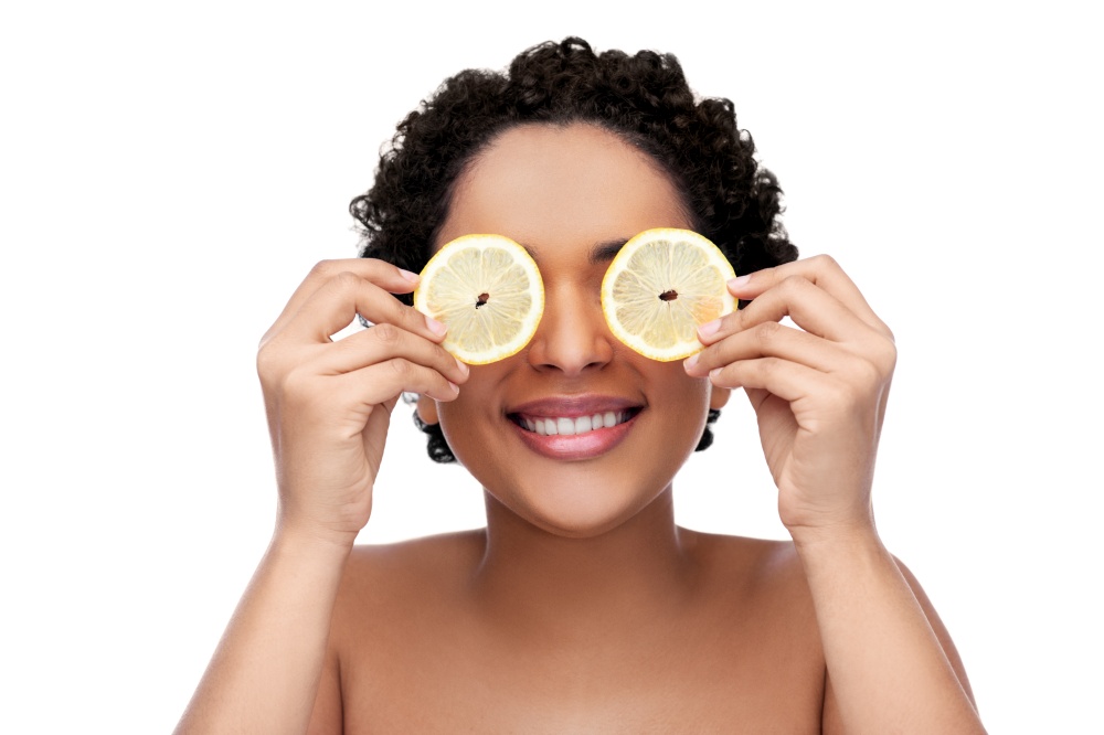 beauty, skin care and detox concept - beautiful african american woman making eye mask of lemons over white background. african american woman making eye mask of lemons