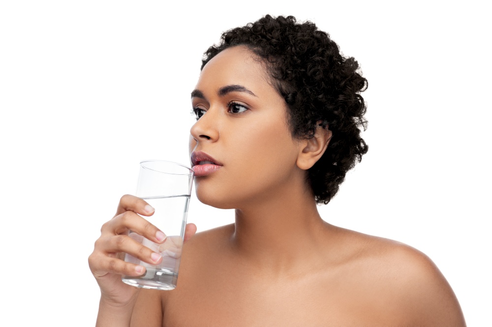 beauty and people concept - portrait of young african american woman with bare shoulders with glass of water over white background. young african american woman with glass of water