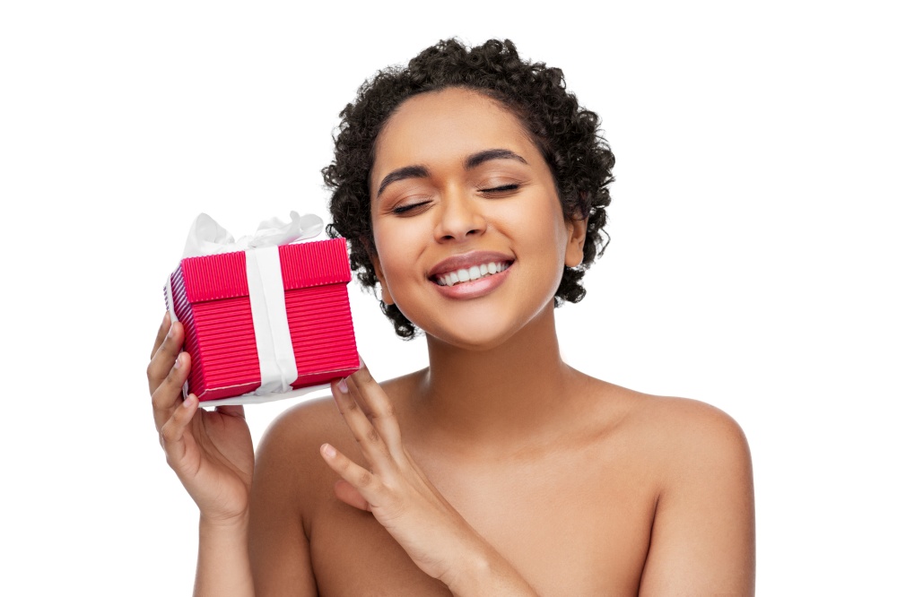 beauty, holidays and people concept - portrait of happy smiling young african american woman with bare shoulders holding gift box over white background. portrait of young african american woman with gift