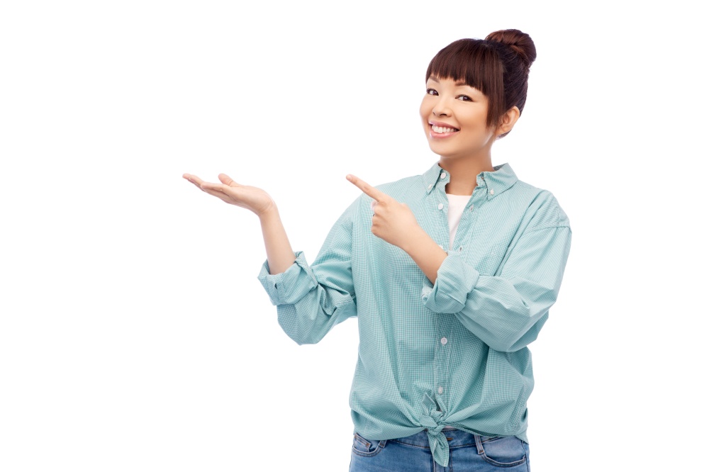 people and advertisement concept - happy asian young woman holding something imaginary on empty hand over white background. happy asian woman holding something on hand