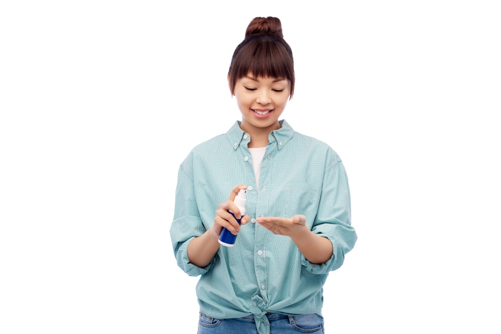 health care, safety and people concept - happy smiling asian woman using hand sanitizer over white background. happy smiling asian woman using hand sanitizer