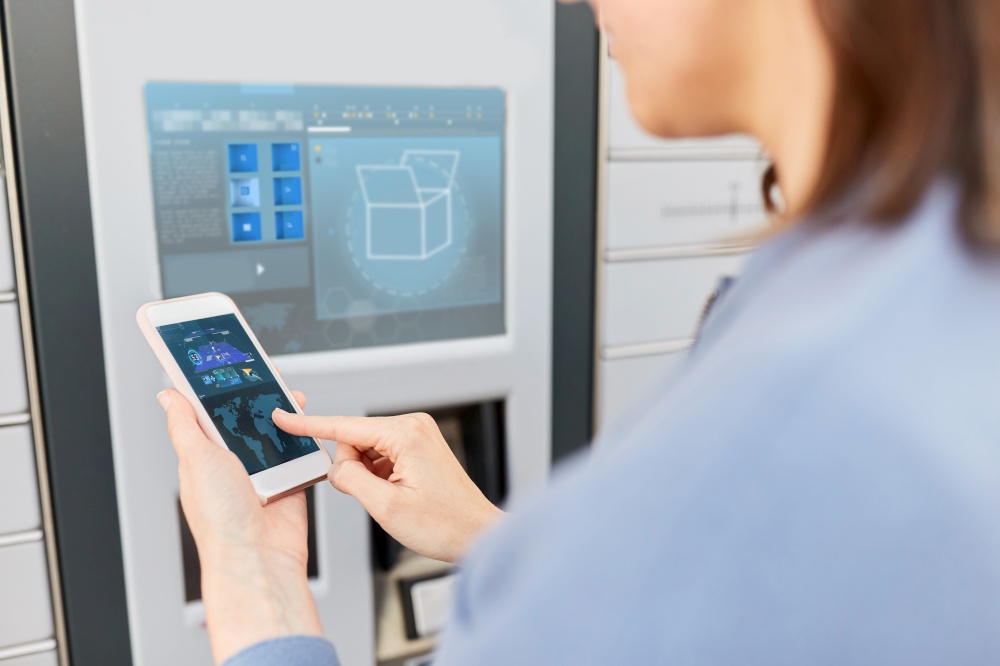 mail delivery, technology and post service concept - close up of woman with smartphone choosing operation on outdoor automated parcel machine&rsquo;s touch screen. woman with smartphone at automated parcel machine