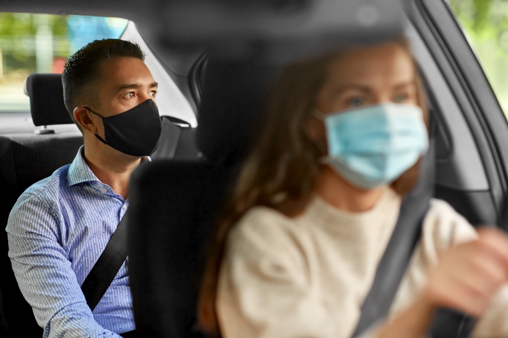 transportation, health and people concept - female driver driving car with male passenger wearing face protective medical mask for protection from virus disease. female driver in mask driving car with passenger