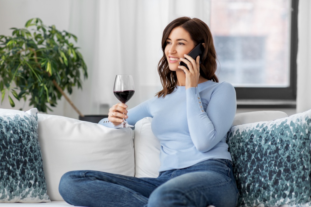 leisure and people concept - happy woman calling on smartphone and drinking red wine at home. woman calling on smartphone and drinking red wine