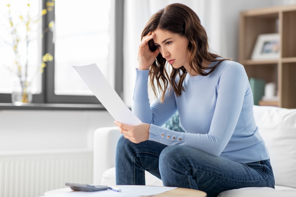 accounting, taxes and finances concept - stressed young woman with papers and calculator at home. stressed woman with papers and calculator at home