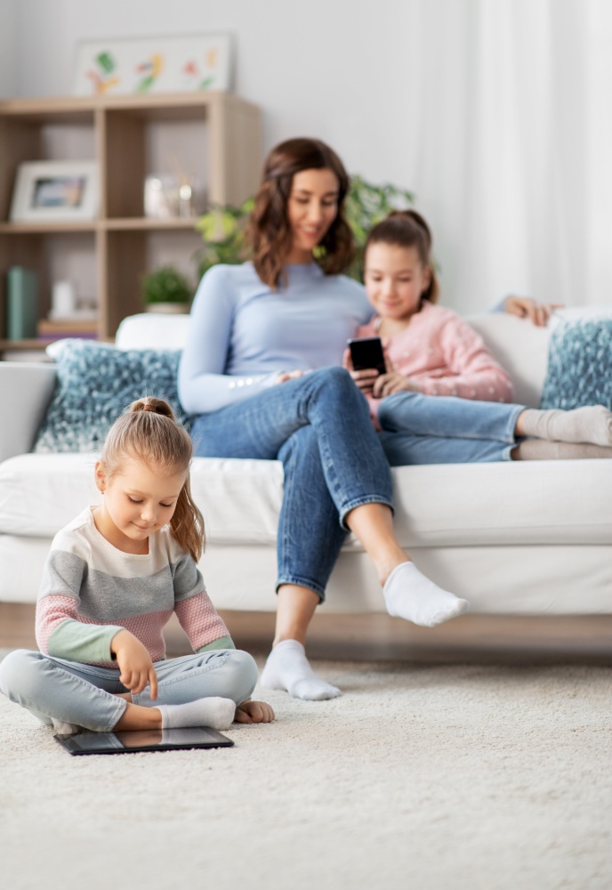 people, family and technology concept - happy mother and two daughters with smartphone at home. happy mother and daughters with smartphone at home