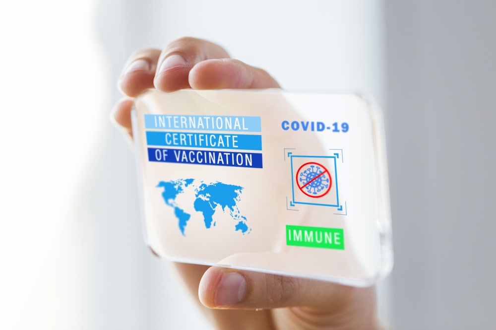 technology and health care concept - close up of hand holding and showing smartphone with international certificate of vaccination or virtual immunity passport on screen. hand holding phone with certificate of vaccination