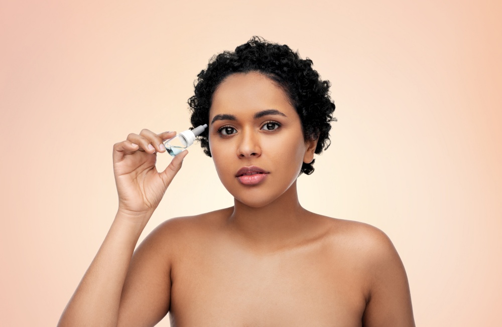 medicine, beauty and vision people concept - portrait of beautiful african american young woman with eye drops over beige background. young african american woman with eye drops
