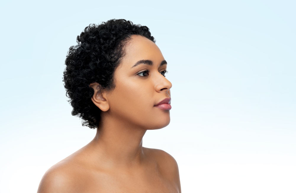 beauty and people concept - portrait of young african american woman with bare shoulders over blue background. portrait of young african american woman
