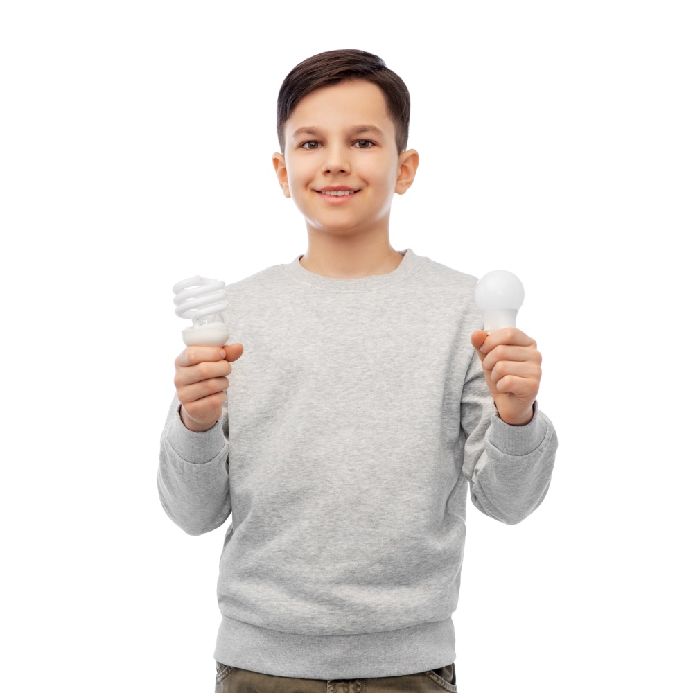 eco living and sustainability concept - smiling boy comparing energy saving light bulb with incandescent lamp over white background. smiling boy comparing different light bulbs