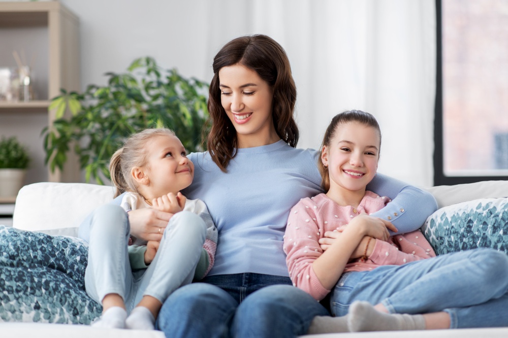 people, family and love concept - happy smiling mother with two daughters at home. happy smiling mother with two daughters at home