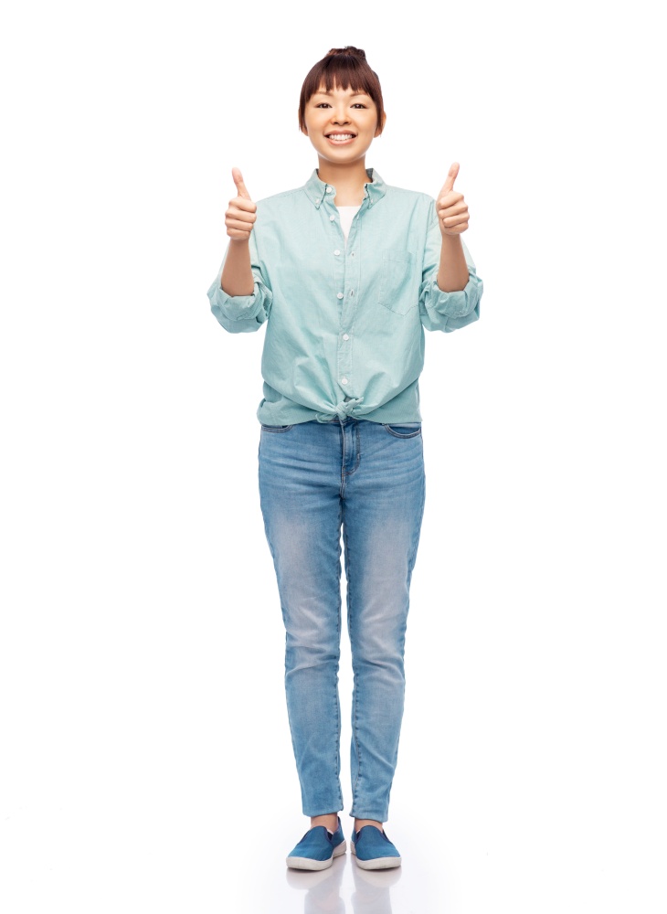 people, ethnicity and gesture concept - happy asian young woman in cotton shirt and jeans over white background. happy asian woman over white background