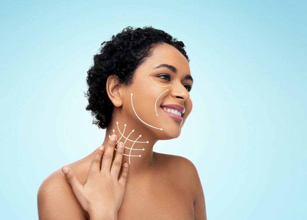beauty, plastic surgery and people concept - happy smiling young african american woman with arrows on face and neck over blue background. young african american woman with arrows on face