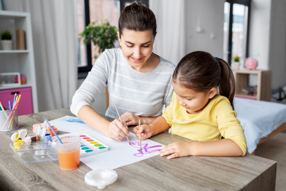 family, motherhood and leisure concept - mother spending time with her little daughter drawing with colors at home. mother with little daughter drawing at home
