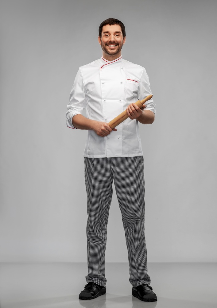 cooking, culinary and people concept - happy smiling male chef or baker with rolling pin over grey background. happy smiling male chef or baker with rolling pin