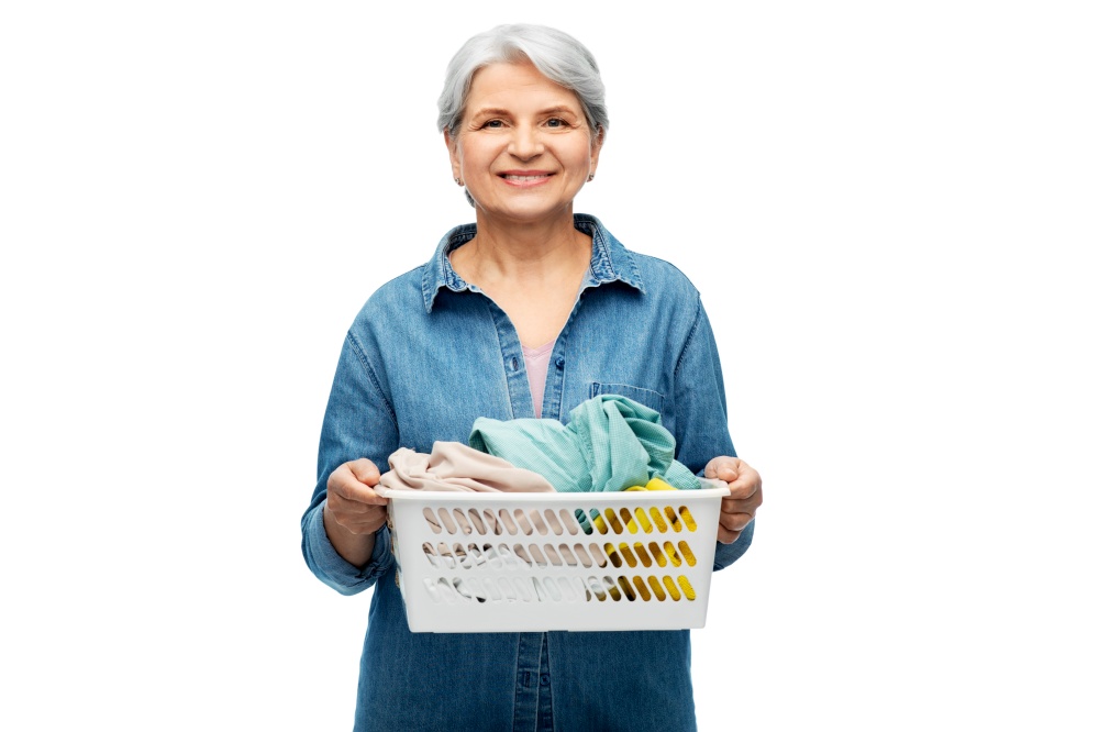 cleaning, wash and old people concept - portrait of smiling senior woman in denim shirt with towels in laundry basket over white background. smiling senior woman with laundry basket
