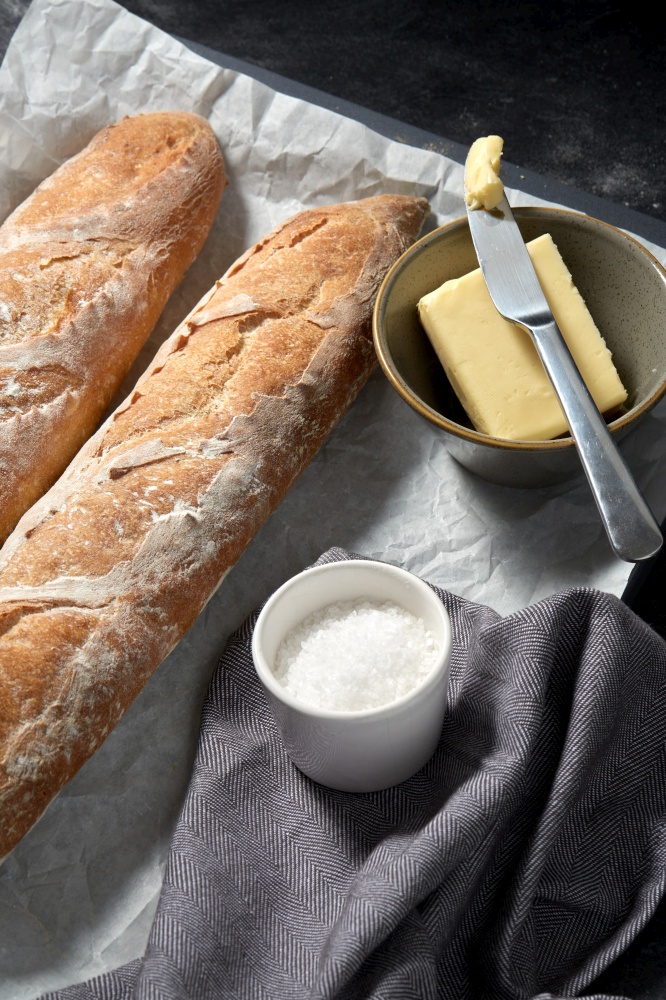 food, baking and cooking concept - close up of bread, butter in bowl and table knife on towel. close up of bread, butter and knife on towel