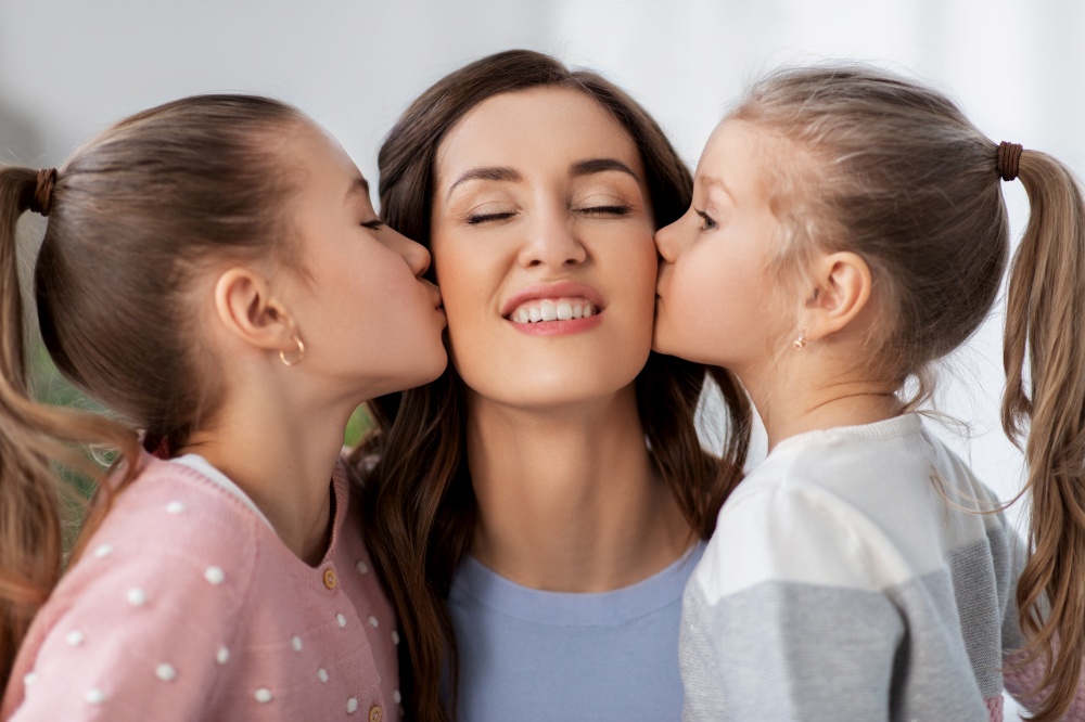 people, family and love concept - two daughters kissing happy mother at home. happy mother and two daughters kissing her at home