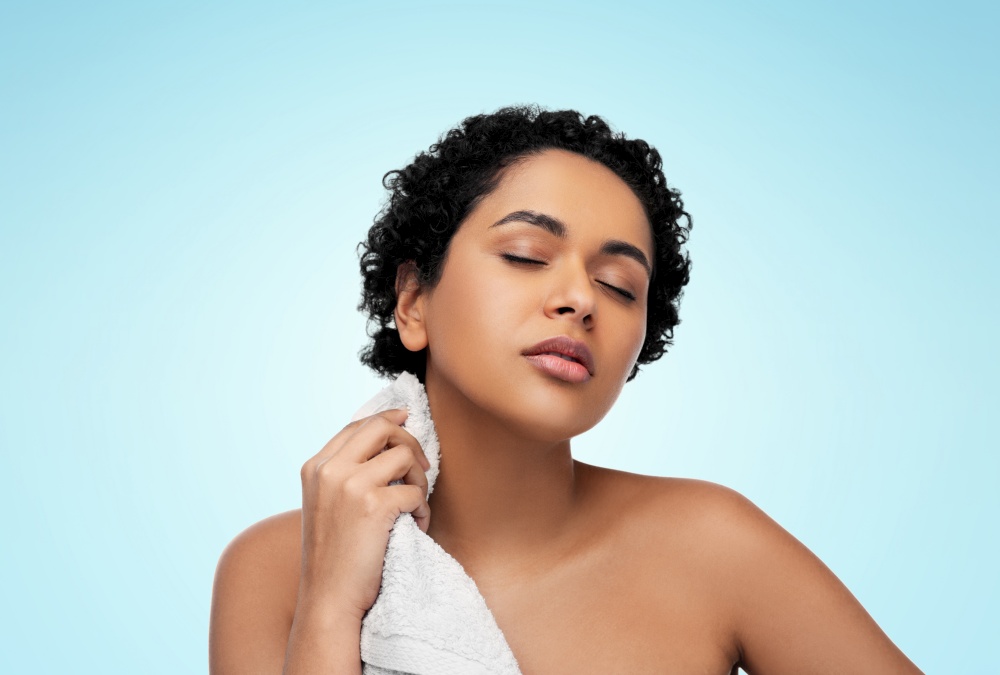 beauty and people concept - portrait of young african american woman with bath towel over blue background. young african american woman with bath towel