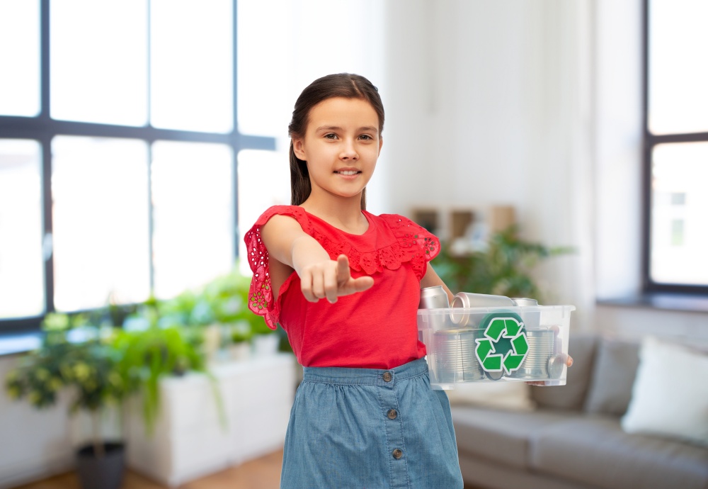 metal recycling, waste sorting and sustainability concept - smiling girl holding plastic box with tin cans pointing finger to camera over home living room background. smiling girl sorting metallic waste at home
