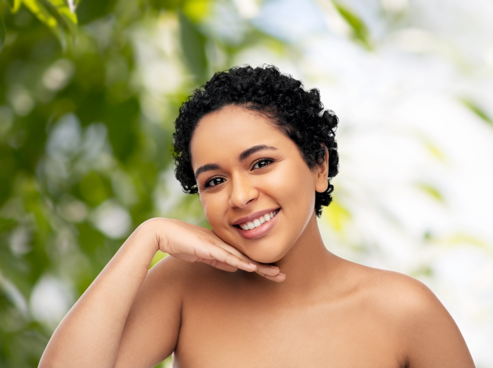 beauty and people concept - portrait of happy smiling young african american woman with bare shoulders over green natural background. portrait of young african american woman