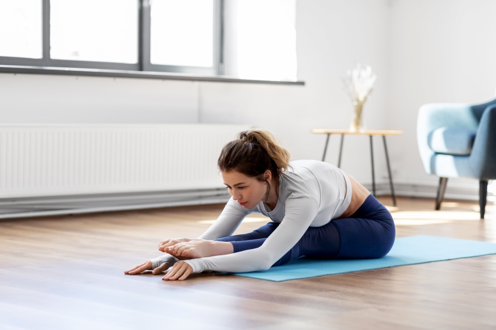 fitness, sport and healthy lifestyle concept - young woman doing yoga exercises on mat at home. young woman doing yoga exercise at home