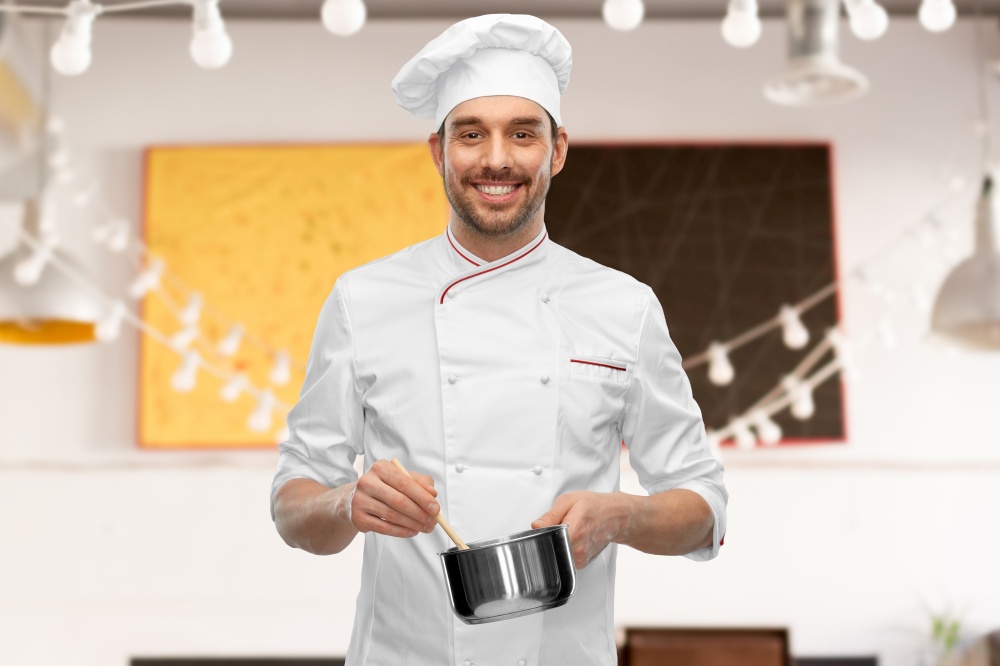 cooking, culinary and people concept - happy smiling male chef in toque with pot or saucepan over restaurant background. happy smiling male chef with saucepan cooking food