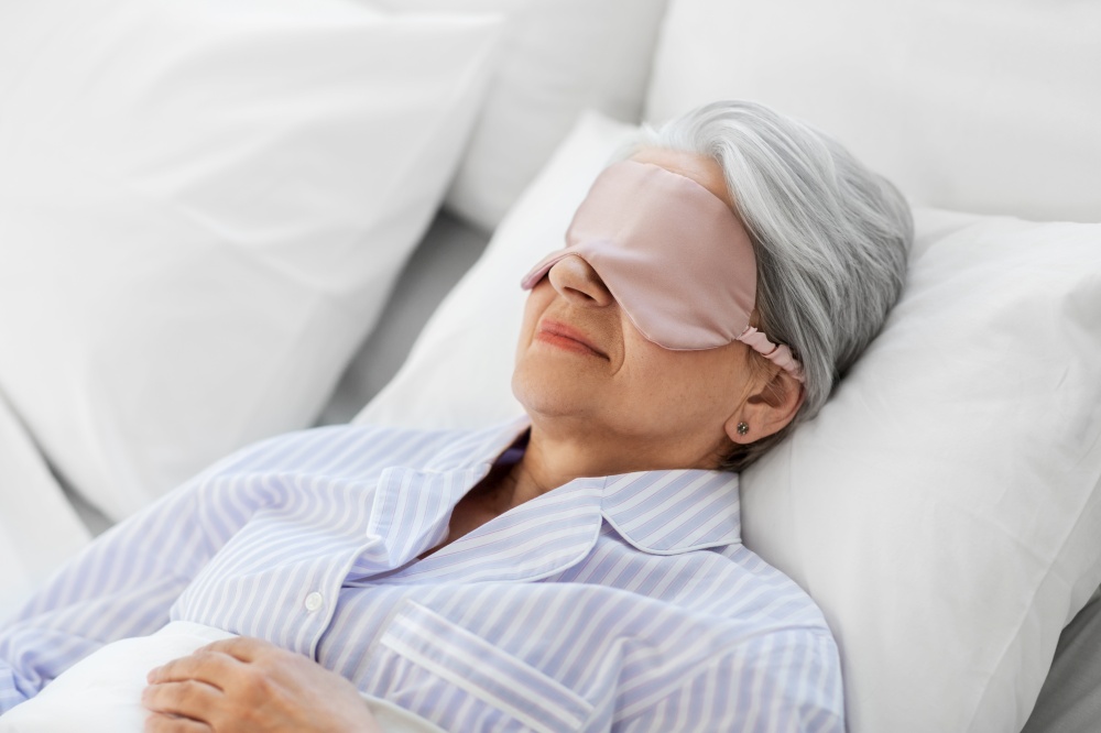 old age and people concept - senior woman with eye mask sleeping in bed at home bedroom. senior woman with eye mask sleeping in bed at home