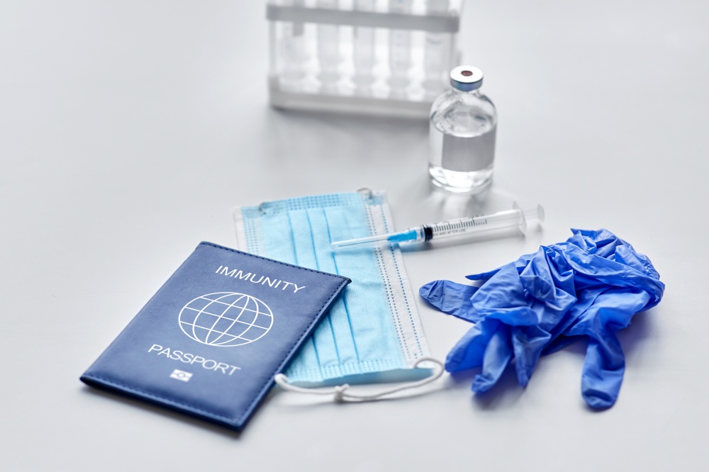 medicine, vaccination and healthcare concept - immunity passport with mask, syringe, vaccine and test tubes with protective medical gloves on white table. immunity passport, mask, syringe, vaccine on table