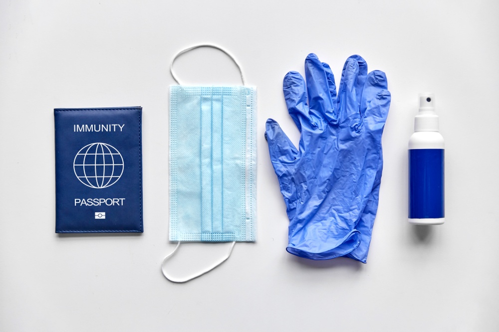health protection, pandemic and disinfection concept - immunity passport, medical mask, gloves and hand sanitizer in spray on white table. immunity passport, mask, gloves and hand sanitizer