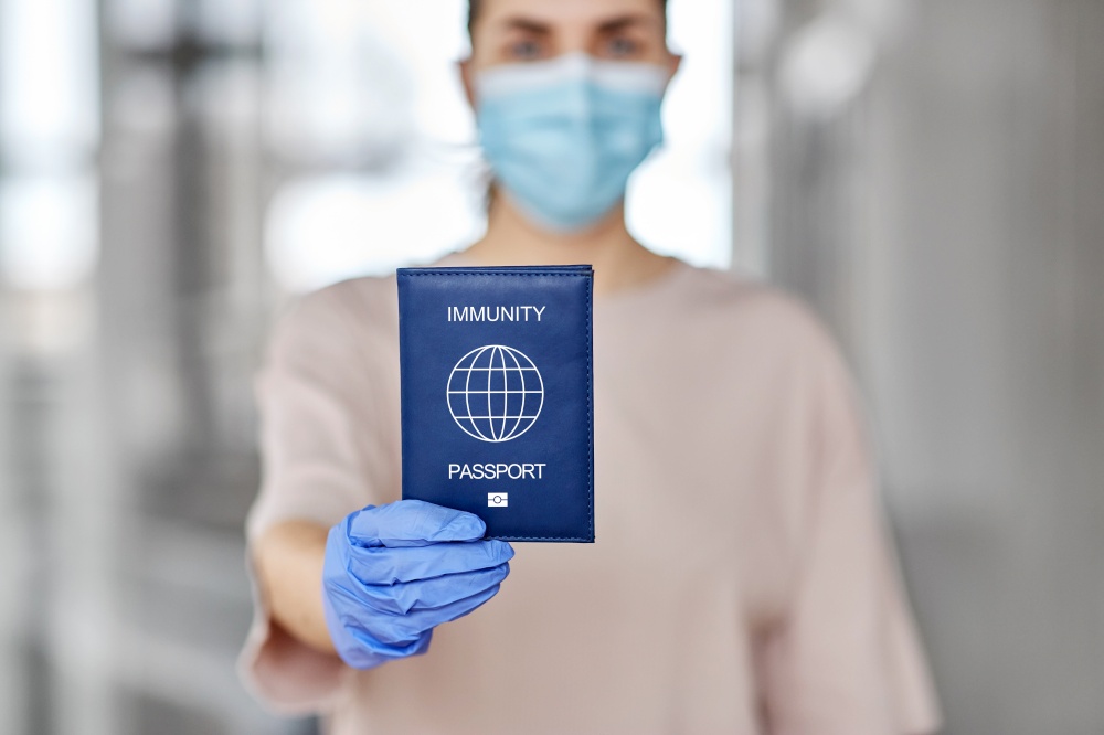 health protection, vaccination and pandemic concept - close up of woman in mask and gloves holding immunity passport. woman in mask and gloves holding immunity passport