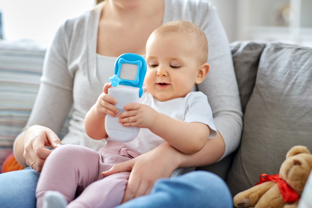 family, motherhood and people concept - mother and little baby playing with toy phone at home. mother with baby playing with toy phone at home