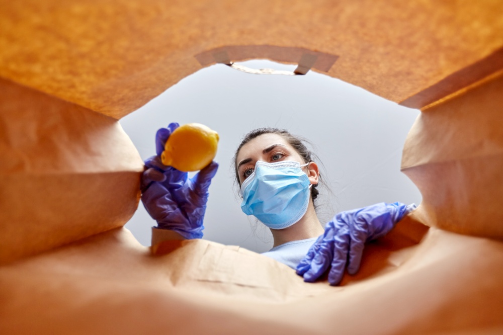 health protection, home delivery and pandemic concept - woman in protective medical gloves and mask taking food from paper bag. woman in gloves and mask with food in paper bag