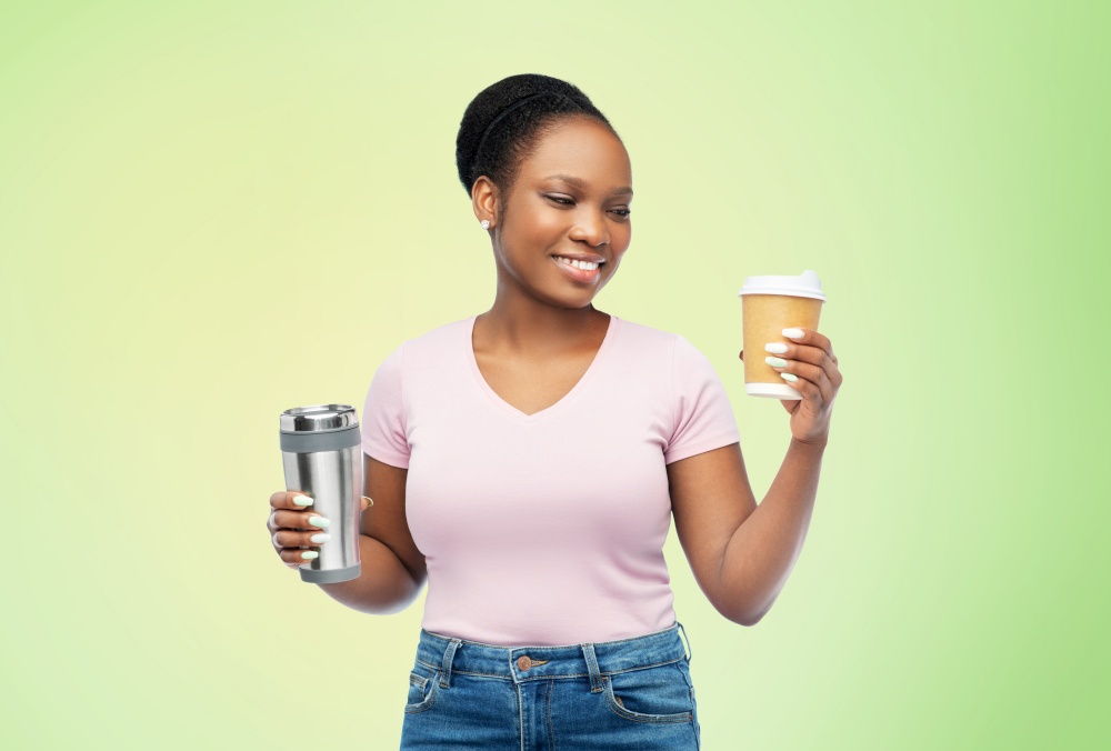 sustainability and people concept - portrait of happy smiling young african american woman with coffee cup and tumbler for hot drinks over green background. woman with coffee cup and tumbler for hot drinks