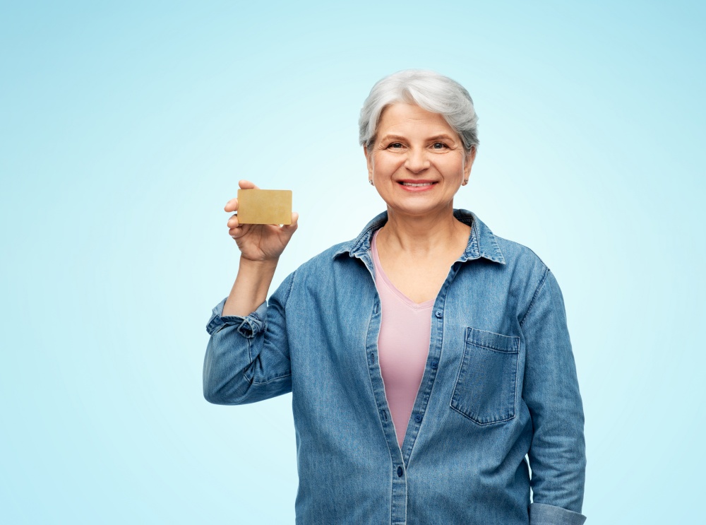 money, finance and old people concept - portrait of smiling senior woman with credit card over blue background. portrait of smiling senior woman with credit card