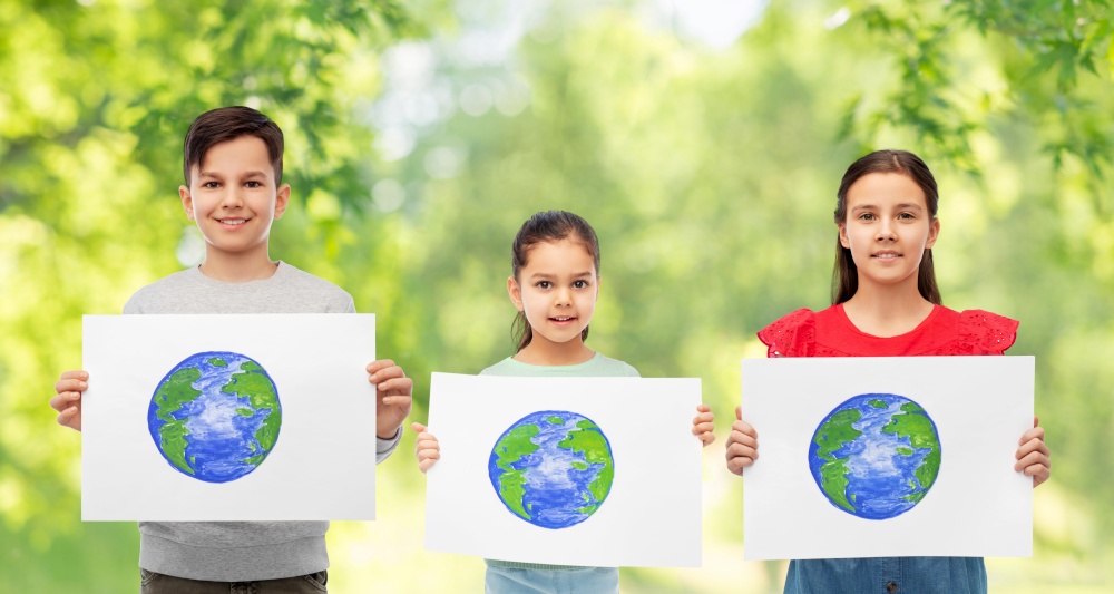 eco living, environment and sustainability concept - smiling girls and boy holding drawing of earth planet over green natural background. smiling children holding drawing of earth planet