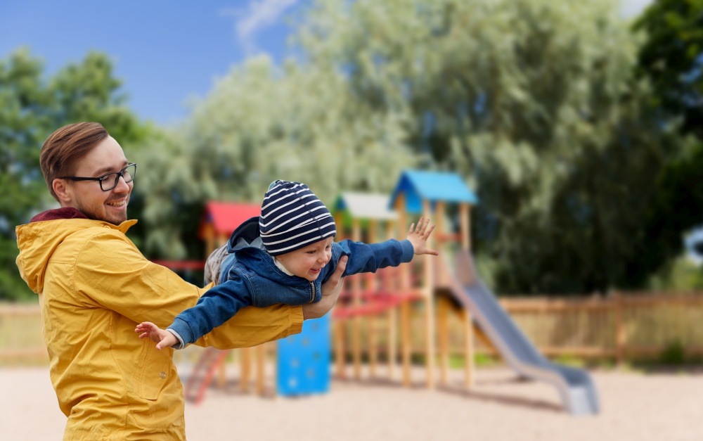 family, childhood, fatherhood, leisure and people concept - happy father and little son playing and having fun over children&rsquo;s playground background. father with son playing and having fun outdoors